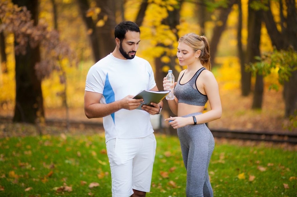 Fitness. Personal Trainer Takes Notes While Woman Exercising Outdoor